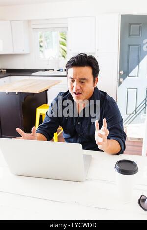 Reife Geschäftsmann mit Händen öffnen arbeiten am Laptop am Küchentisch Stockfoto