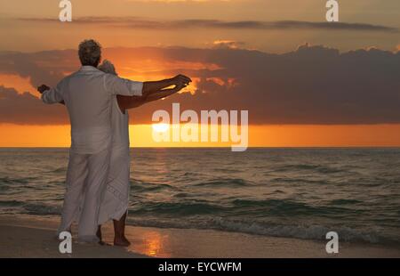 Älteres Paar am Strand bei Sonnenuntergang Stockfoto