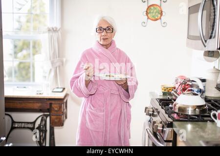 Ältere Frau im Küche hält Teller mit Essen Stockfoto