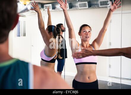 Mitte Erwachsene Frau im Yoga-Kurs mit erhobenen Armen Stockfoto