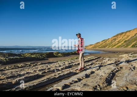 Junge Mann stand am Strand mit Blick auf Meer Stockfoto