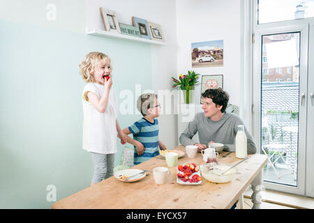 Vater und Kinder essen Waffeln in Küche Stockfoto