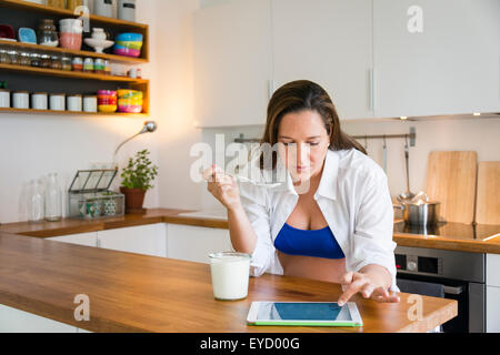 Schwangere Frau isst Joghurt mit tablet Stockfoto
