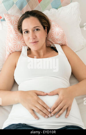 Schwangere Frau, Herzform auf Magen Stockfoto