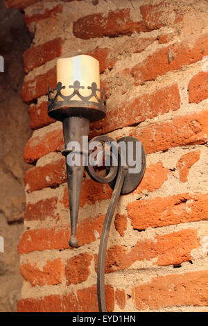 Taschenlampe mit Kerzenlicht auf der Grunge-Wand im Untergeschoss eines alten Schlosses Stockfoto