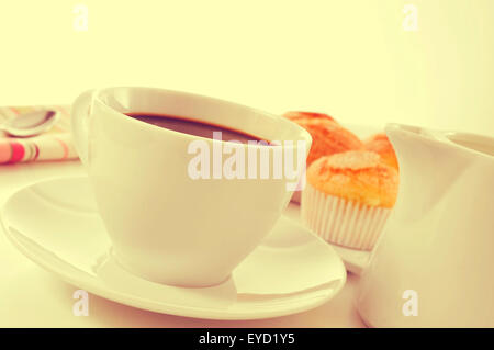 Nahaufnahme von einer Tasse Kaffee und ein Haufen von Magdalenas, die typisch spanische schlicht Muffins, in einem weißen Teller auf einem gedeckten Tisch mit einer Stockfoto