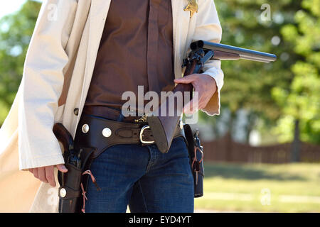 Eine Nahaufnahme Bild von einem bewaffneten Cowboy mit einer Schrotflinte und zwei Seitenarme in einer Parade in ländlichen Alberta, Kanada. Stockfoto