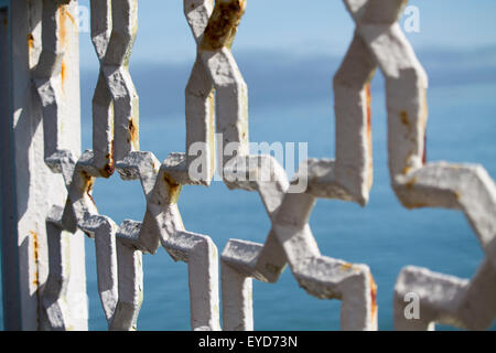 Eine verrostete weißen Geländer auf einer Mole mit Blick auf das Meer. Stockfoto