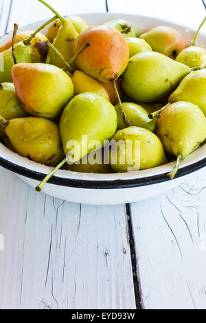 Haufen von Frische und reife Birnen in einer Metallschale auf weißer Holztisch Stockfoto