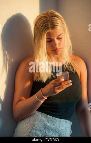Eine blonde Teenager-Mädchen mit nassen Haaren verkleidet und fertig zum Ausgehen am Abend Sonnenlicht Stockfoto