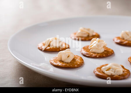 Kräcker mit Frischkäse auf weißen Teller für den kleinen Hunger Stockfoto