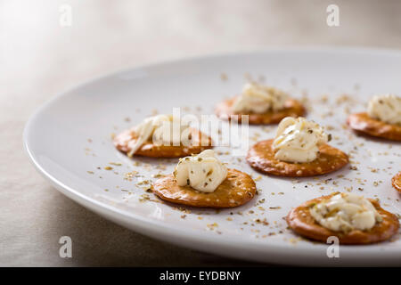 Kräcker mit Frischkäse auf weißen Teller für einen Snack mit oregano Stockfoto