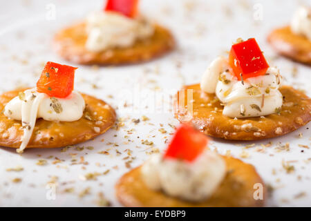 Nahaufnahme von Cracker mit Frischkäse auf einem weißen Teller Stockfoto