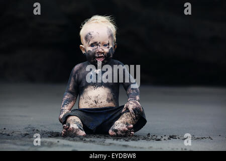 Lustige Porträt des lächelnden Kind mit dreckiges Gesicht sitzen und