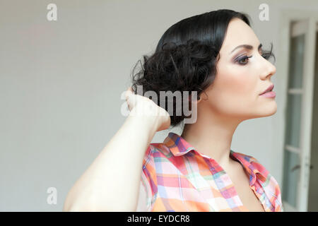 Wunderschöne Frau-Profil und eine sehr feminine Atitude während der Umsetzung gerade ihr Haar. Stockfoto