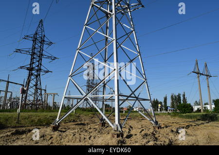 Hochspannungsleitungen und Strommasten in eine flache und grüne Agrarlandschaft an einem sonnigen Tag mit Cirruswolken am blauen Himmel Stockfoto