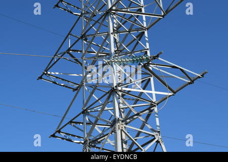 Hochspannungsleitungen und Strommasten in eine flache und grüne Agrarlandschaft an einem sonnigen Tag mit Cirruswolken am blauen Himmel Stockfoto