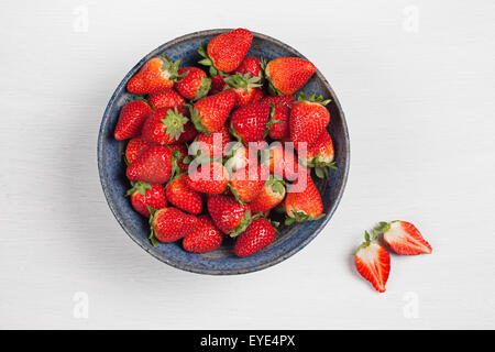 Eine Schale mit Erdbeeren auf weißem Hintergrund mit einem halbierten Erdbeeren Stockfoto