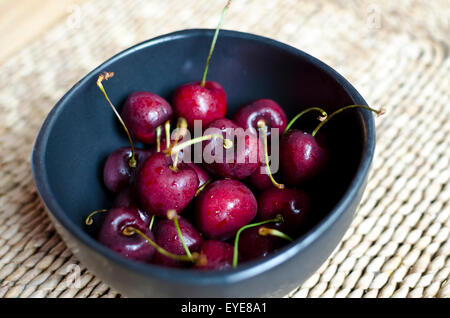 Schüssel mit Süßkirschen in einer schwarzen Schale. Stockfoto