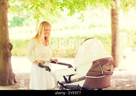 glückliche Mutter mit Kinderwagen im park Stockfoto