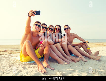 Freunde mit Smartphones am Strand Stockfoto