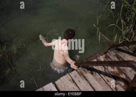 Ein 17 jähriger Junge betritt einen Süßwasser-See in Kaltern-Kalterer See, Südtirol, Norditalien. Stockfoto