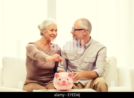 Älteres Paar mit Geld und Sparschwein zu Hause Stockfoto