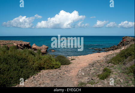 Blick auf das Meer und flauschige weiße Wolken von der Küste von einem einsamen Pebble Beach auf der Insel Menorca Spanien Stockfoto