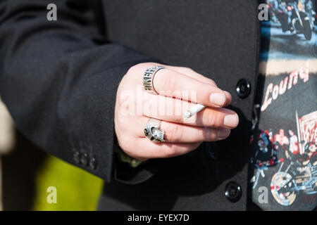 Ein Mann mit einer 'Biker' Ring an seine geballte Faust, während Sie gleichzeitig ein bis Zigarette zwischen den Fingern gerollt Stockfoto