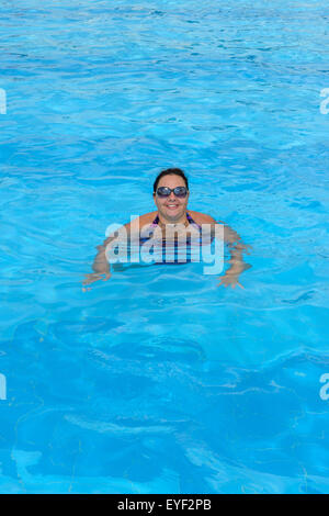 Hohen Winkel anzeigen Mitte Erwachsenen Dame, dass Schwimmen im leuchtend blauen Wasser des Pools. Stockfoto