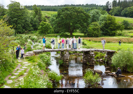 Touristen auf der historischen Klöppel Brücke über den East Dart River in Postbridge, Dartmoor, Devon, England, UK Stockfoto