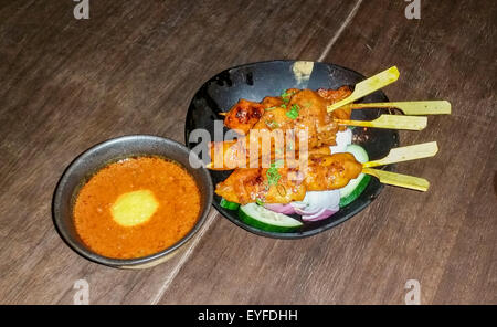 Chicken Satay (Huhn am Spieß) mit Erdnuss-Sauce serviert Kemirinusse, ein Peranakan (eine Mischung aus ethnischen Chinesen/Malaiisch und vieles mehr) Stockfoto