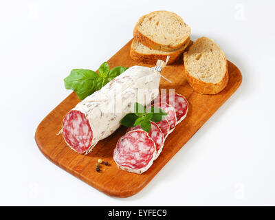 Französische Saucisson Sec und geschnittene knusprige Rolle auf Schneidebrett Stockfoto