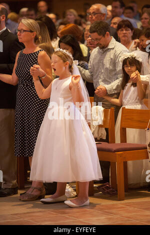 In formalen Erstkommunion Outfits, besuchen multirassische Kinder und ihre Eltern Messe in Laguna Niguel, CA, katholische Kirche für die erste Heilige Kommunion feiern. Beachten Sie gähnende Mädchen. Stockfoto