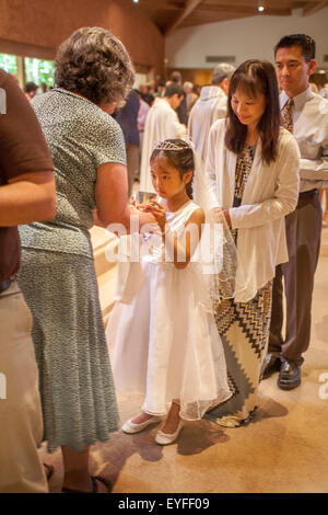 Tragen formalen Outfits, multirassische Kinder und ihre Eltern Line-up für Kommunion in der Messe am Laguna Niguel, CA, katholische Kirche während der Erstkommunion Zeremonien. Hinweis Wein Tasse. Stockfoto