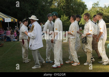 Village Cricket, zwei Teams schütteln am Ende des Cricketspiels die Hand. Sich gegenseitig anzuerkennen und ein Gefühl von Kameradschaft zu zeigen. Eine Geste, die dazu beiträgt, den Geist des Fairplay und des gegenseitigen Respekts aufrechtzuerhalten. Der Schiedsrichter trägt die Grillen-Wicket-Stümpfe. Village Life Sussex England 2015 UK 2000s HOMER SYKES Stockfoto