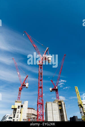 Eine Baustelle mit farbigen hell mobile Baukrane gegen eine lebendige blauen Himmel mit Wolkenfetzen Stockfoto