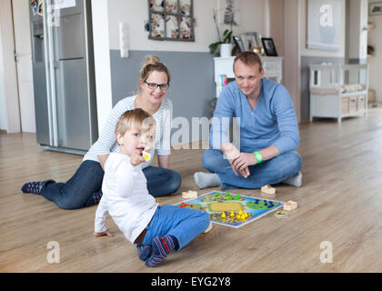 eine Familie sitzt auf dem Boden in die Wohnzimmer und spielen ein Spiel Stockfoto