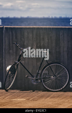 Klassische Vintage schwarzes Fahrrad gelehnt Betonwand, Meer und Wolken im Hintergrund, Retro getönten Bild Stockfoto