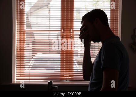 Silhouette des jungen Mannes durch ein Fenster. Stockfoto