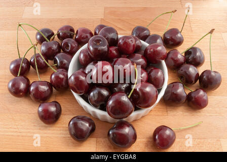 cherries in a white ceramic bowl on the wood table Stockfoto