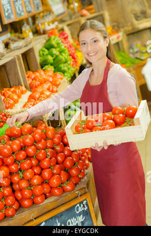 Shop Mitarbeiter tragen eine Kiste Tomaten Stockfoto