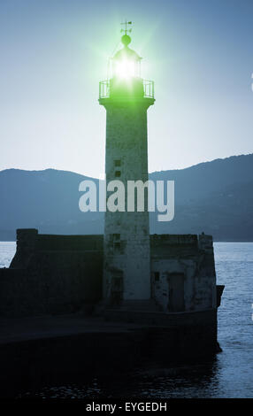 Alten Leuchtturm Turm Silhouette auf der Küste des Mittelmeeres, grünes Licht. Blau getönt, stilisierte Nacht Foto Stockfoto