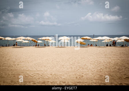 Sonnenschutz liegen und Stroh Schirme an einem Strand am Mittelmeer Stockfoto