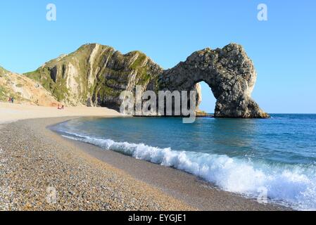 Durdle Door Arch Rock Formation an der Jurassic Coast von Dorset, England, mit Strand und brechender Welle Stockfoto