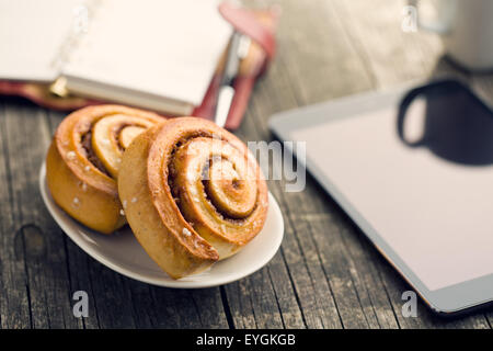 Zimtschnecken, Tasse Kaffee und Computer Tablet. Business-Frühstück. Stockfoto