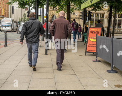 2 kaukasischen Männer zu Fuß entfernt von der Kamera eine hat eine schwarze Jacke der andere hat eine Burgunder Jacke. Stockfoto