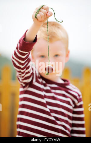 Ein Junge mit einem Conker auf eine Zeichenkette. Warten Teil in einem altmodischen Spiel der Englischen conkers zu nehmen Stockfoto