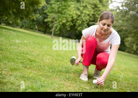 junge Frau einen Golfball auf einem t-Shirt zu platzieren. Stockfoto