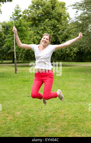 junge Frau mit Freude springen, nachdem ein Hole in one Stockfoto